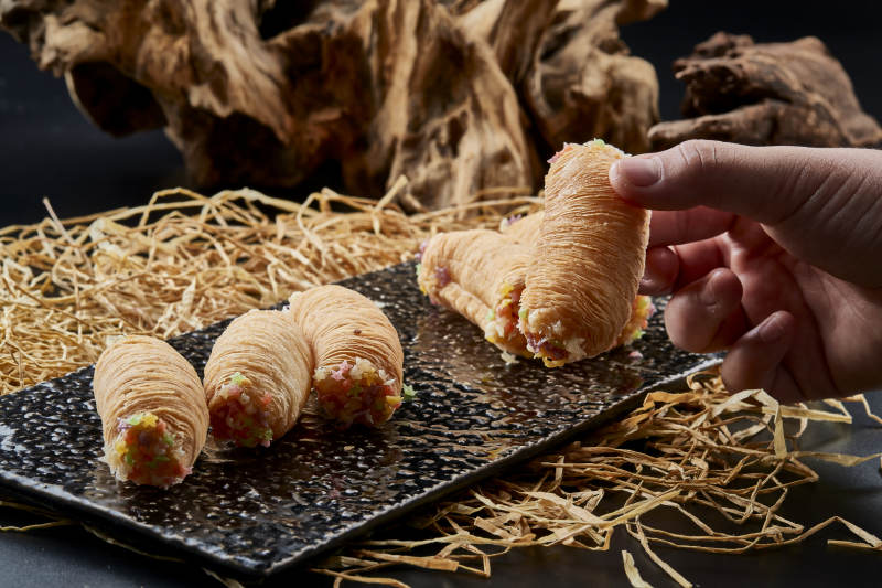 黑色瓷盘装的香酥奶黄蛋酥图片