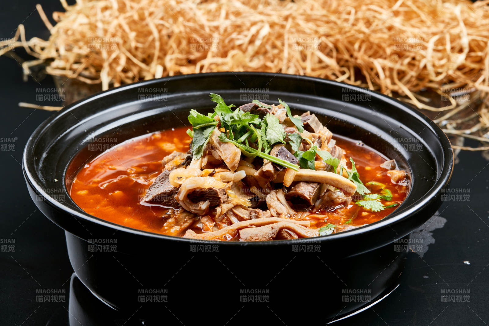 黑色背景上的砂锅香辣红油羊杂煲图片
