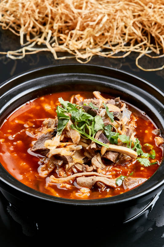 黑色背景上的砂锅香辣红油羊杂煲图片