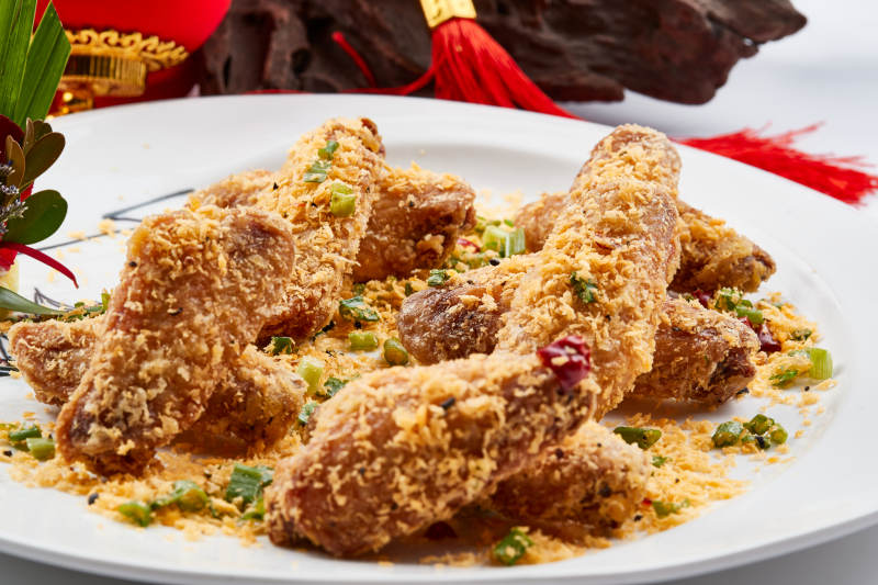 白色瓷盘装的的香炸避风塘鸡翅图片