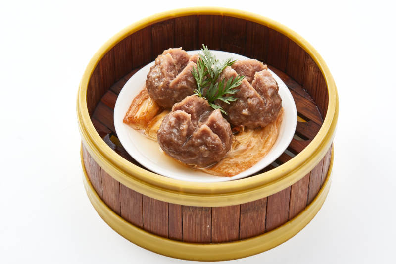 白色背景上精美竹笼屉装的开花牛肉球图片