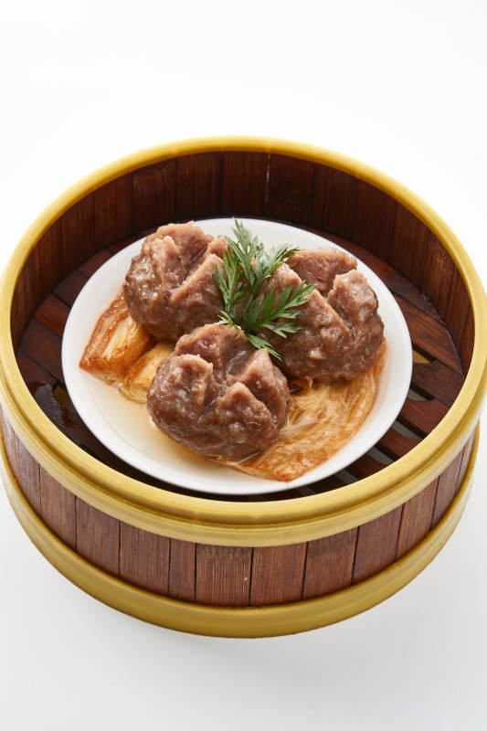 白色背景上精美竹笼屉装的开花牛肉球图片