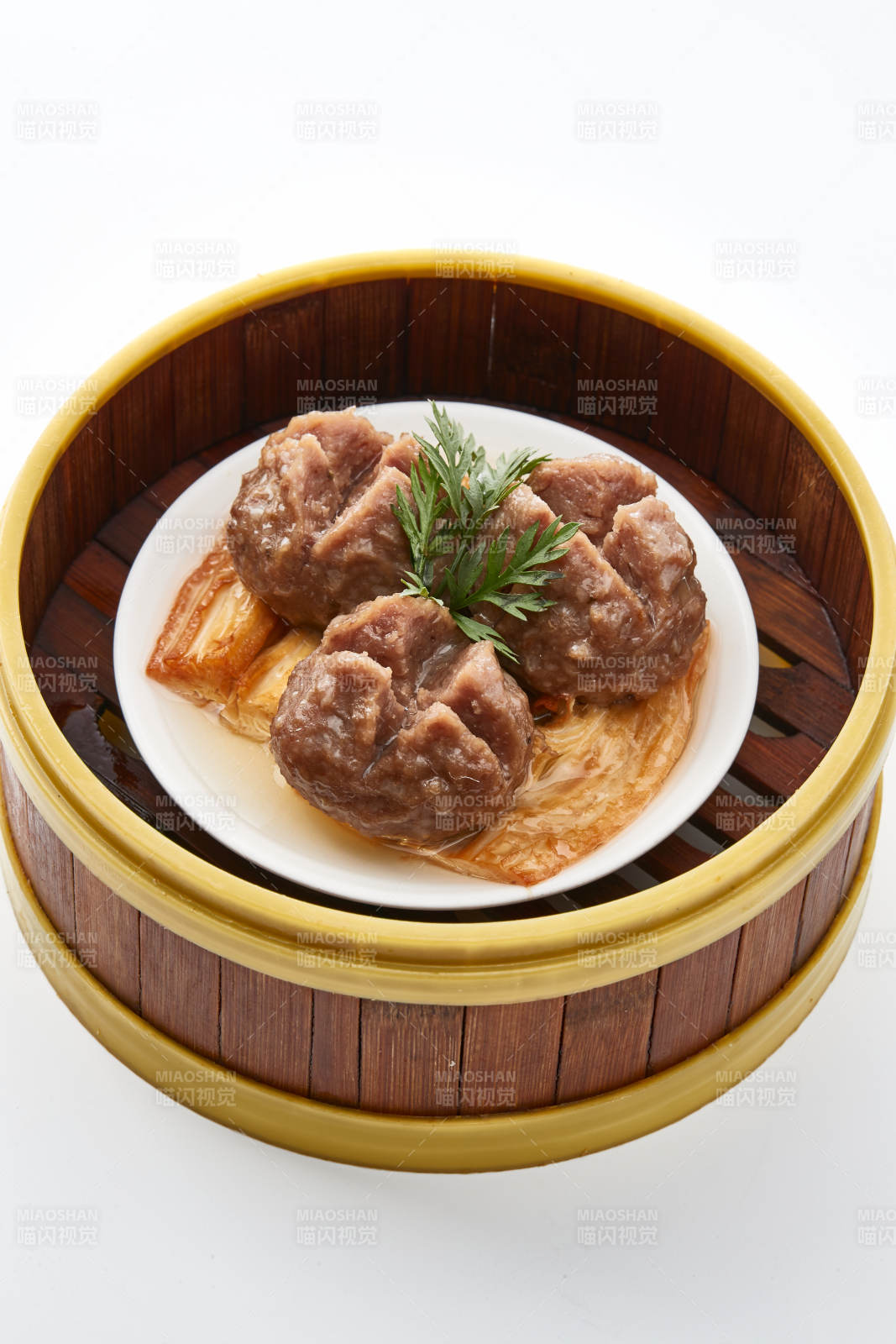 白色背景上精美竹笼屉装的开花牛肉球图片