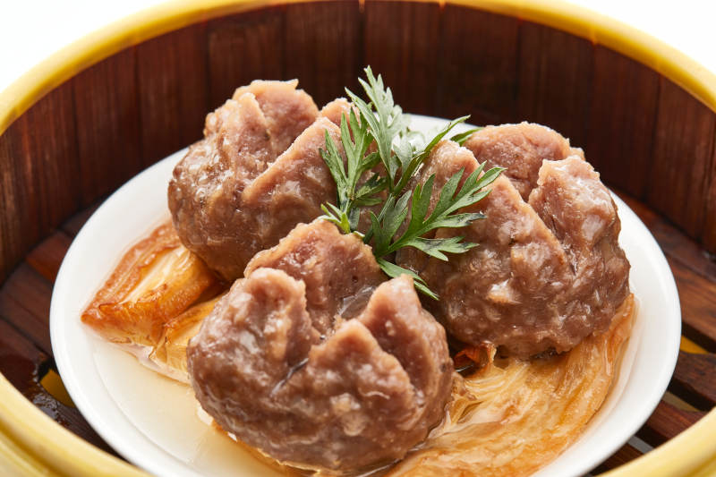 白色背景上精美竹笼屉装的开花牛肉球图片