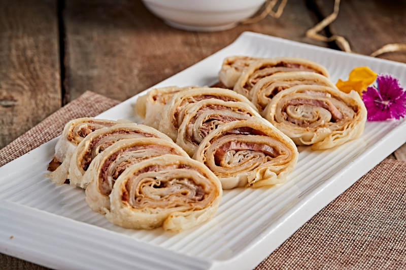 白色瓷盘装的大饼卷熏肉图片