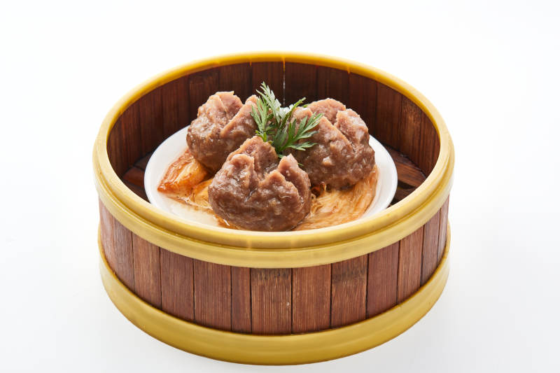 白色背景上精美竹笼屉装的开花牛肉球图片