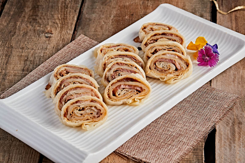 白色瓷盘装的大饼卷熏肉图片