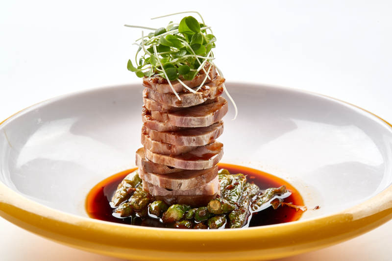 精美瓷盘装的压制熏肘花切片配香椿苗图片