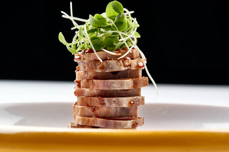 精美瓷盘装的压制熏肘花切片配香椿苗图片