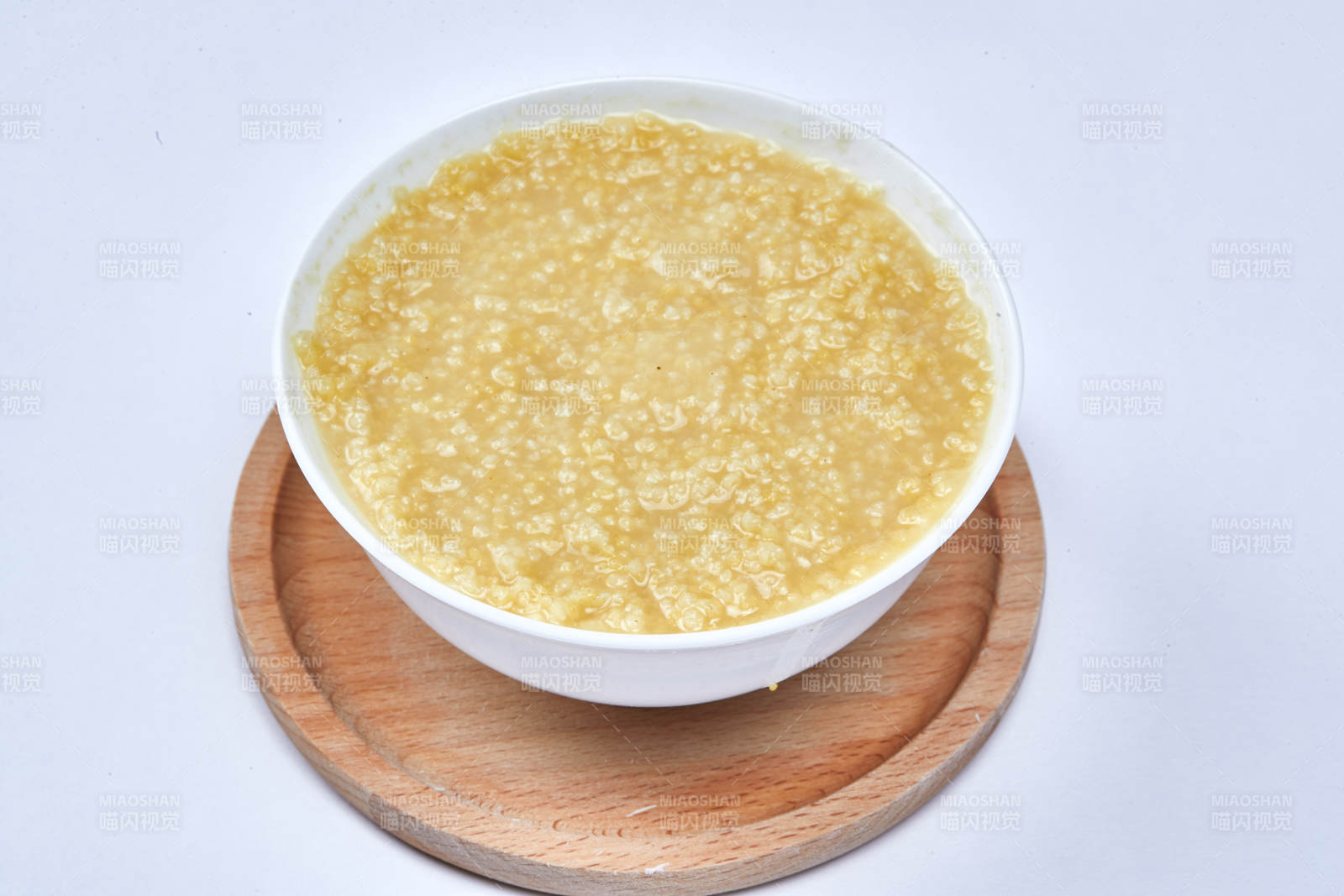 手持木勺㧟起的美味香浓小米粥图片