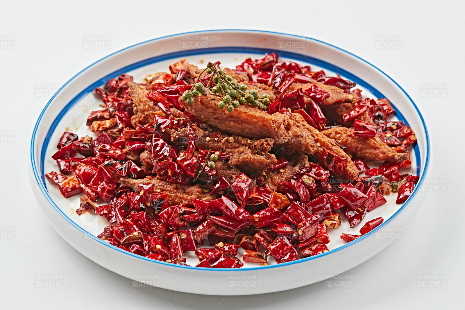 白色瓷盘装的川香油炸麻辣鸡翅中图片