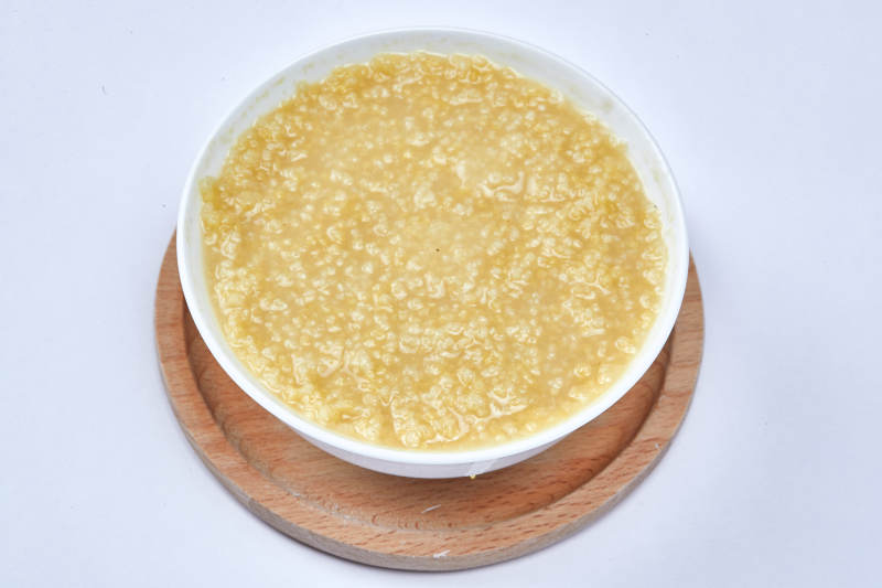 手持木勺㧟起的美味香浓小米粥图片