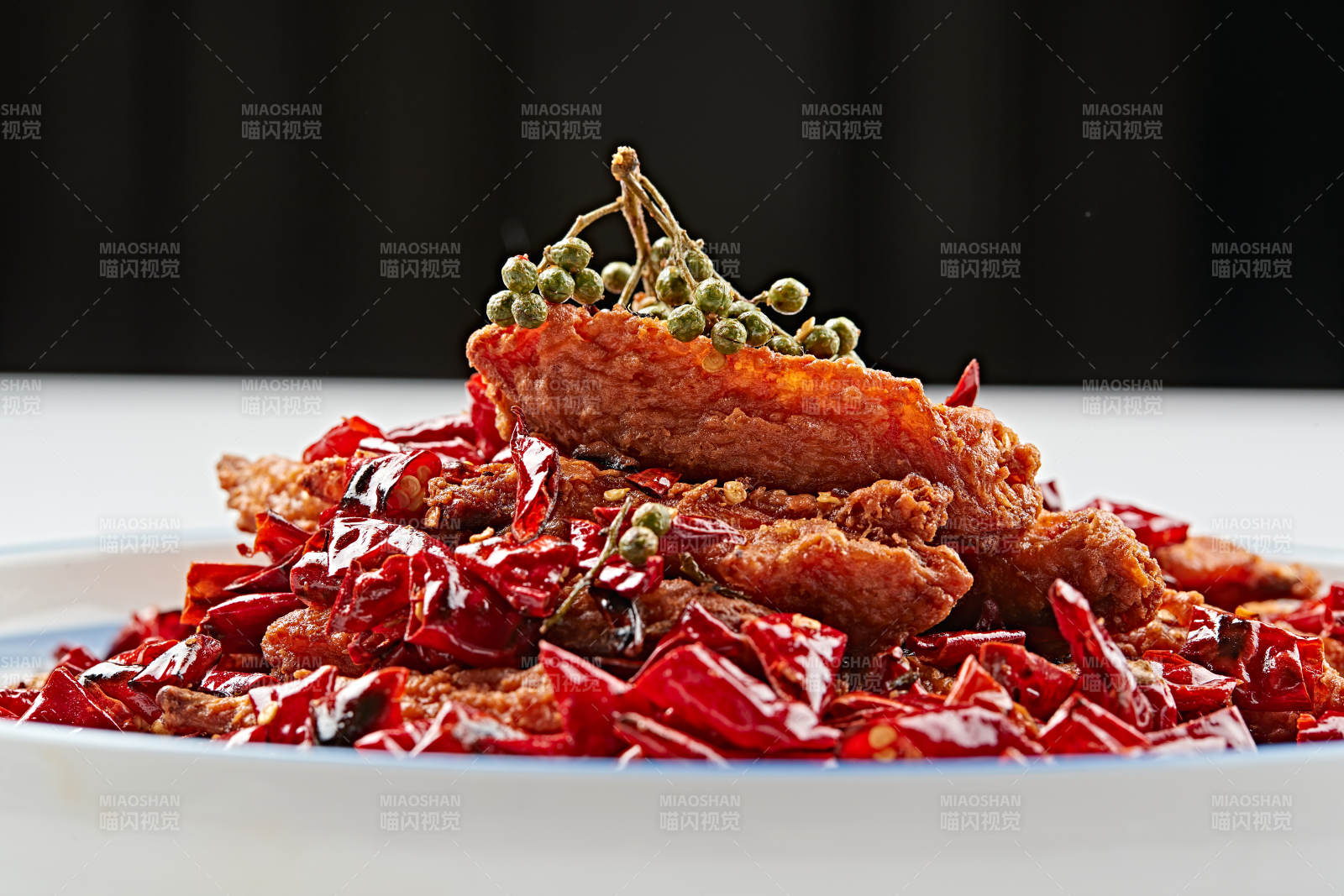 白色瓷盘装的川香油炸麻辣鸡翅中图片