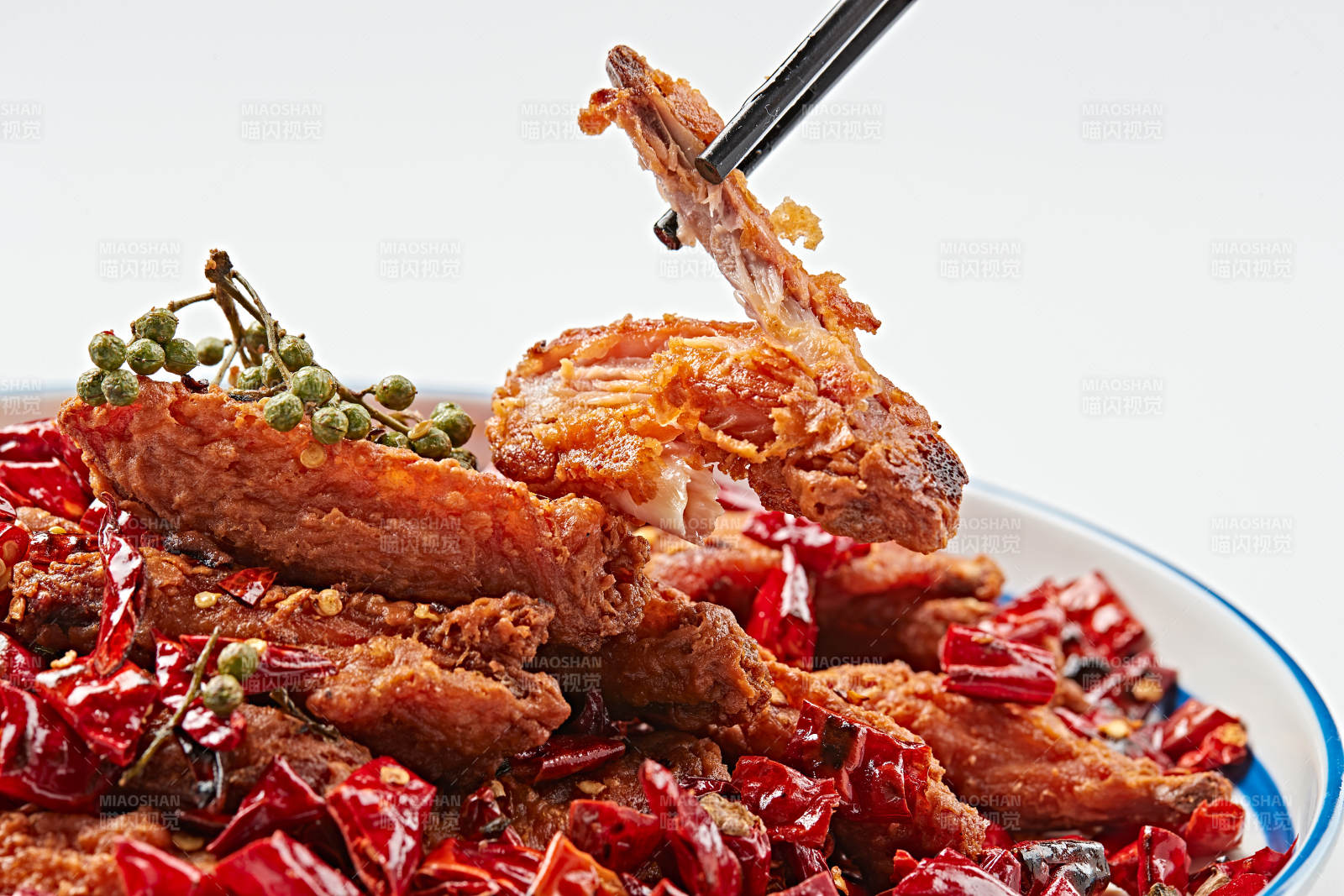 白色瓷盘装的川香油炸麻辣鸡翅中图片