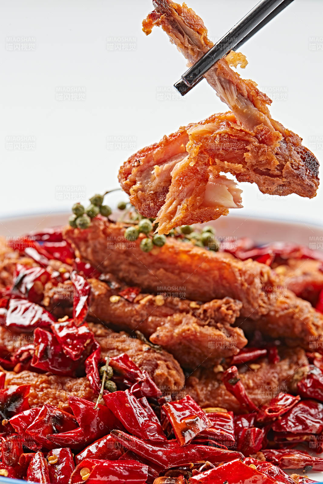 白色瓷盘装的川香油炸麻辣鸡翅中图片