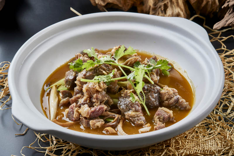 白色砂锅装的蒜苗浓汤炖牛腩图片