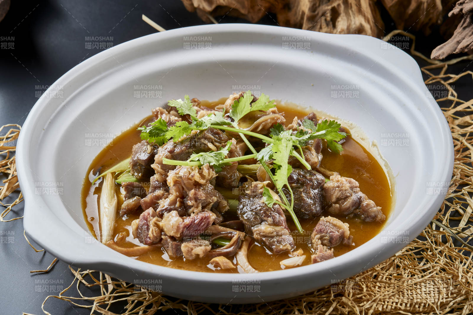 白色砂锅装的蒜苗浓汤炖牛腩图片