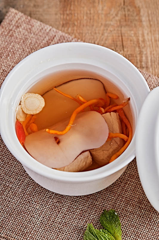 白色瓷汤盅装的木薯党参虫草花炖老鸭汤图片