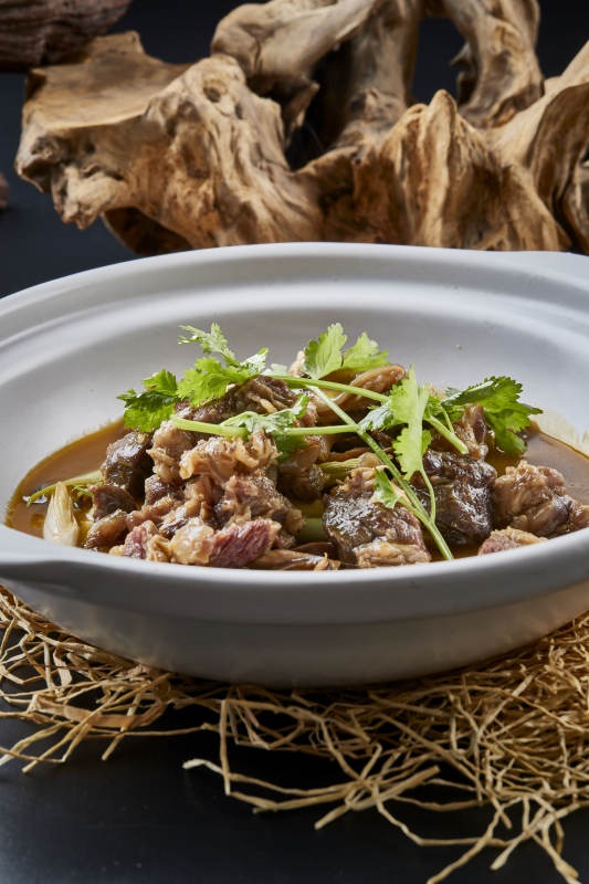 白色砂锅装的蒜苗浓汤炖牛腩图片