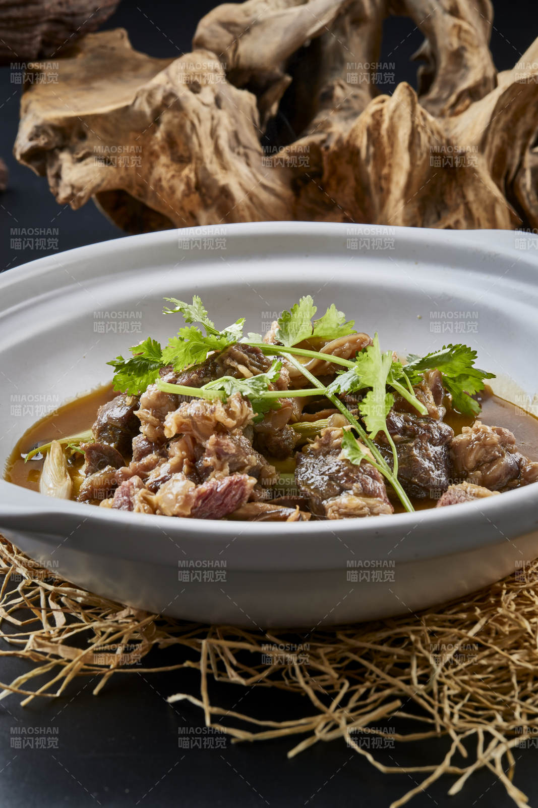 白色砂锅装的蒜苗浓汤炖牛腩图片