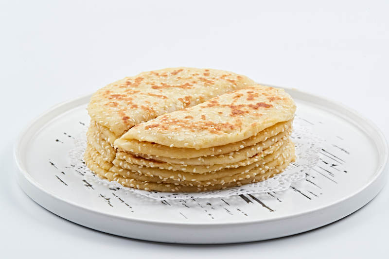 白色瓷盘装的现烙葱油酥饼图片