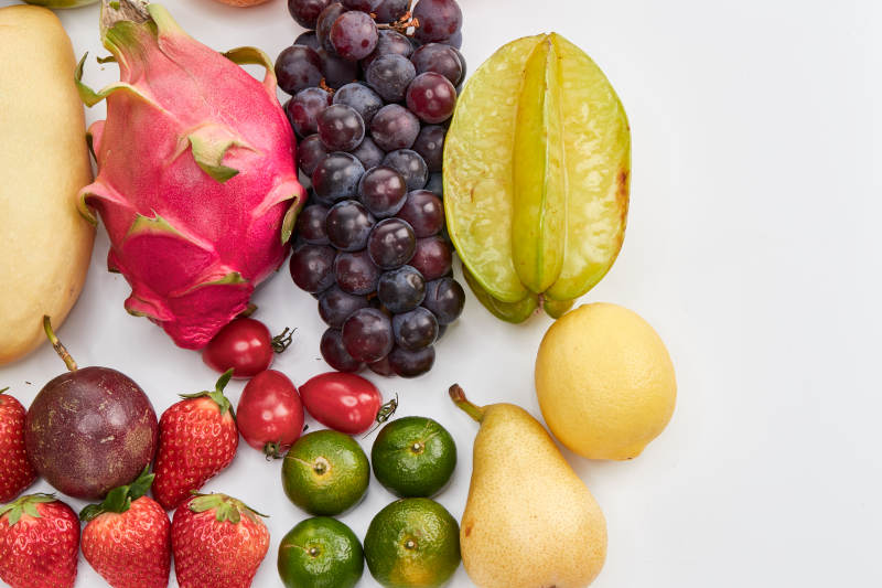 白色背景上摆放的生鲜混合水果图片