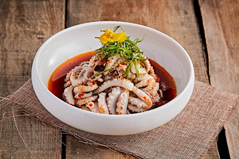 白色瓷盘装的红油醋腌章鱼爪图片