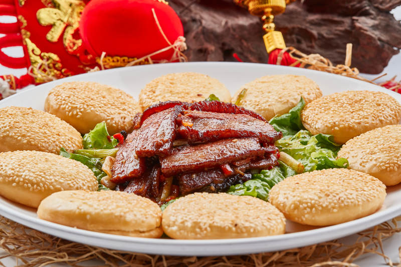 白色瓷盘装的芝麻锅盔肉夹馍图片