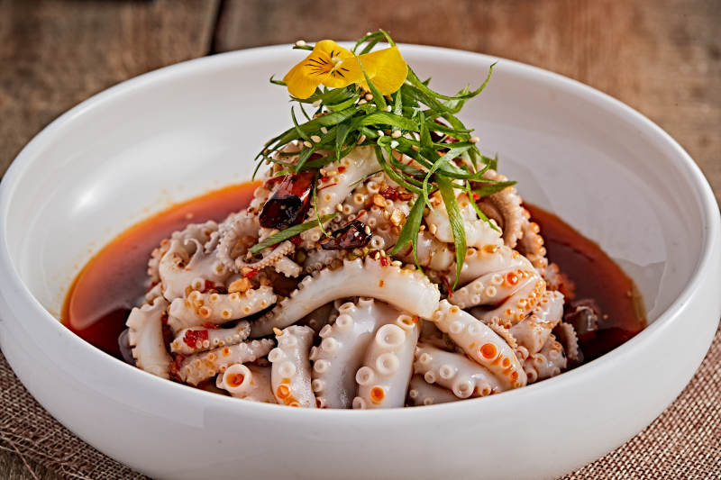 白色瓷盘装的红油醋腌章鱼爪图片