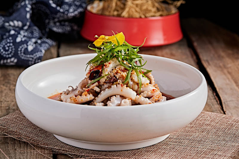 白色瓷盘装的红油醋腌章鱼爪图片