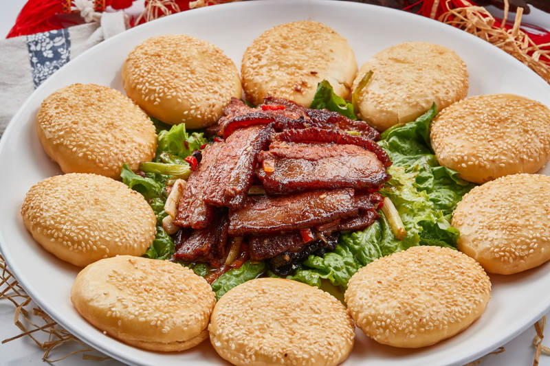 白色瓷盘装的芝麻锅盔肉夹馍图片