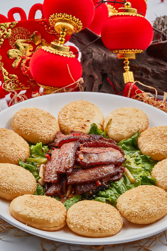 白色瓷盘装的芝麻锅盔肉夹馍图片