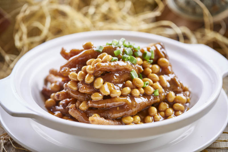 白色砂锅装的黄豆焖鸡脚凤爪图片