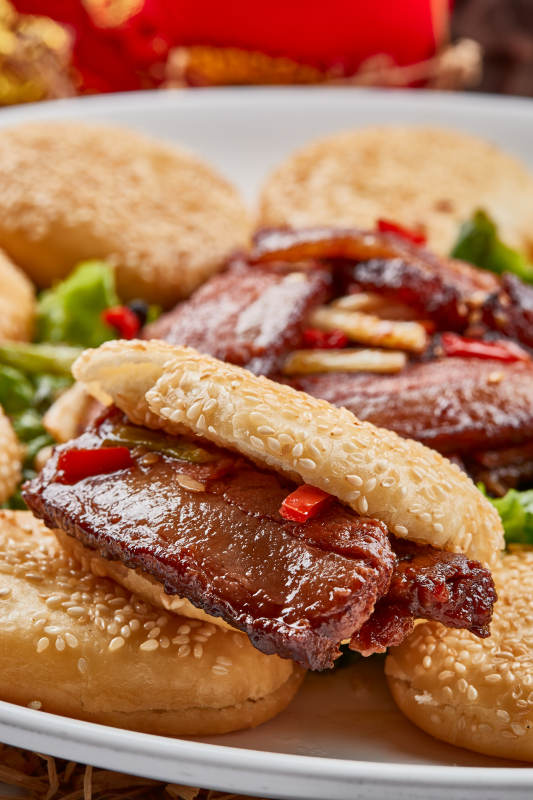 白色瓷盘装的芝麻锅盔肉夹馍图片