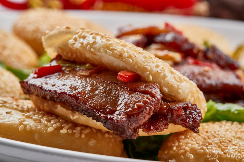 白色瓷盘装的芝麻锅盔肉夹馍图片