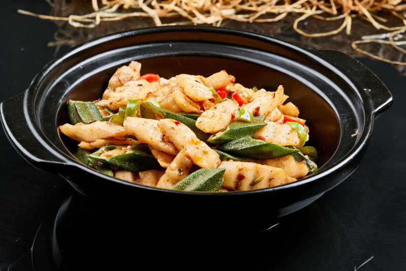 黑色背景上的香辣砂锅秋葵长山药图片