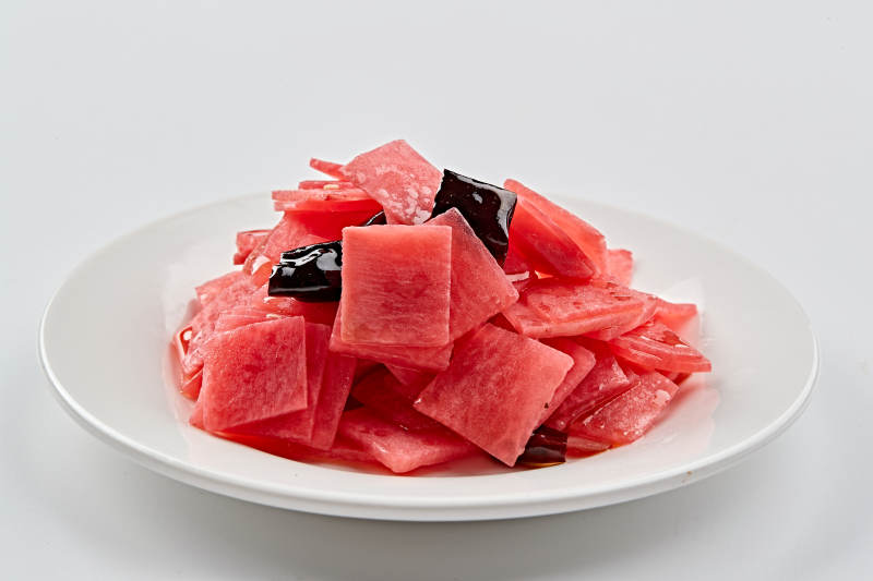 白色瓷盘装的红醋香辣萝卜皮图片