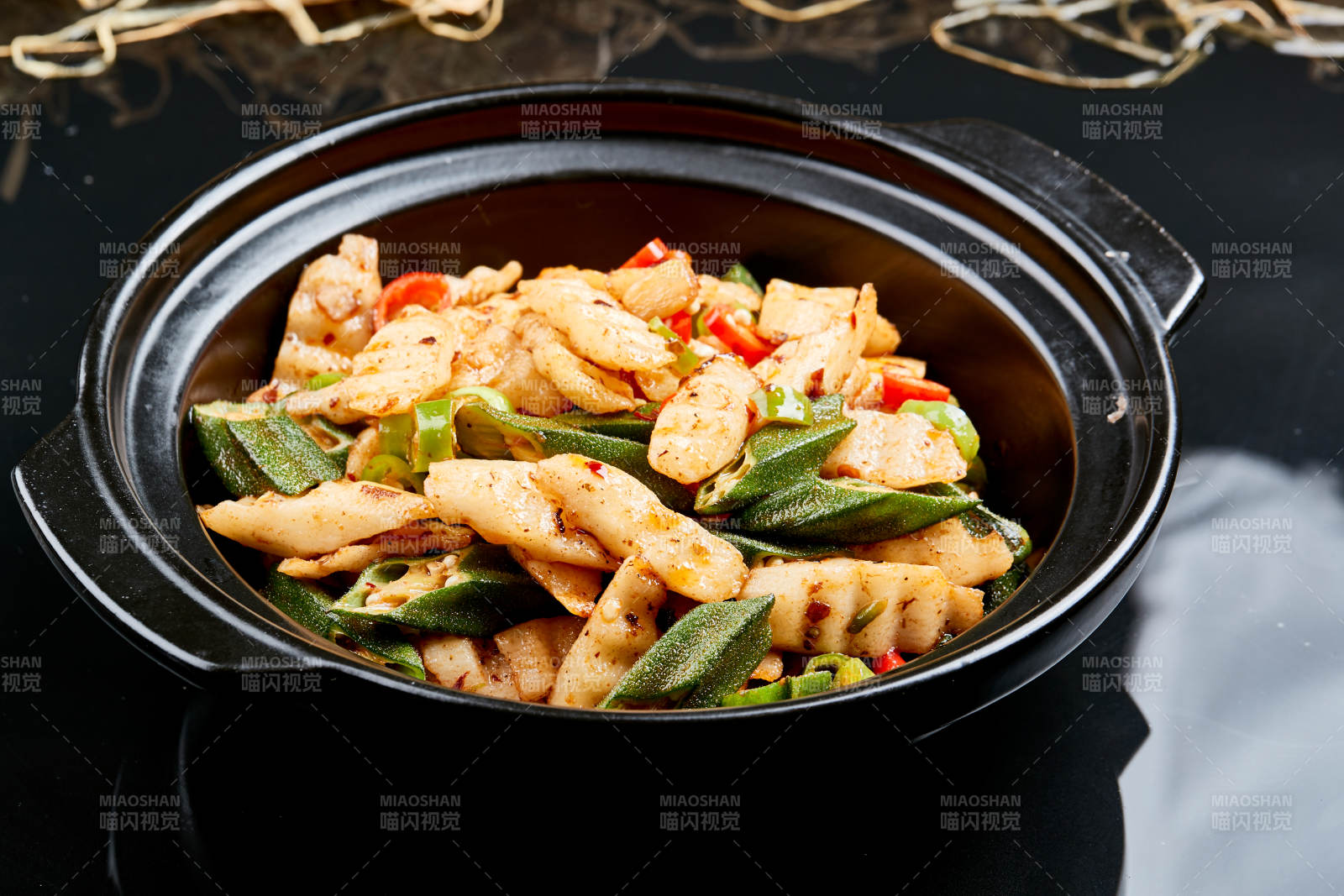 黑色背景上的香辣砂锅秋葵长山药图片