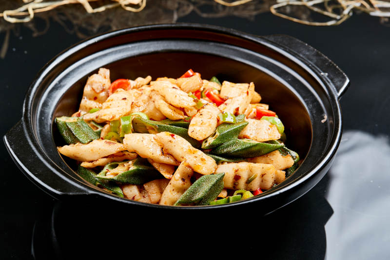 黑色背景上的香辣砂锅秋葵长山药图片