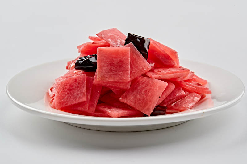 白色瓷盘装的红醋香辣萝卜皮图片