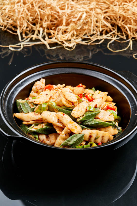 黑色背景上的香辣砂锅秋葵长山药图片