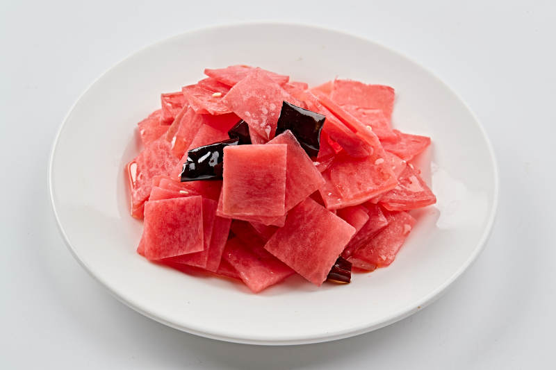 白色瓷盘装的红醋香辣萝卜皮图片