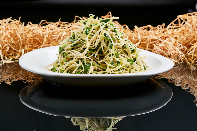 白色瓷盘装的凉拌香椿黑豆苗图片