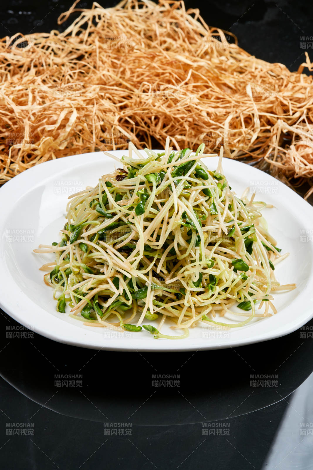 白色瓷盘装的凉拌香椿黑豆苗图片