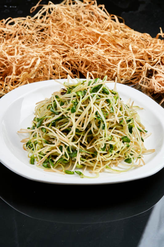 白色瓷盘装的凉拌香椿黑豆苗图片