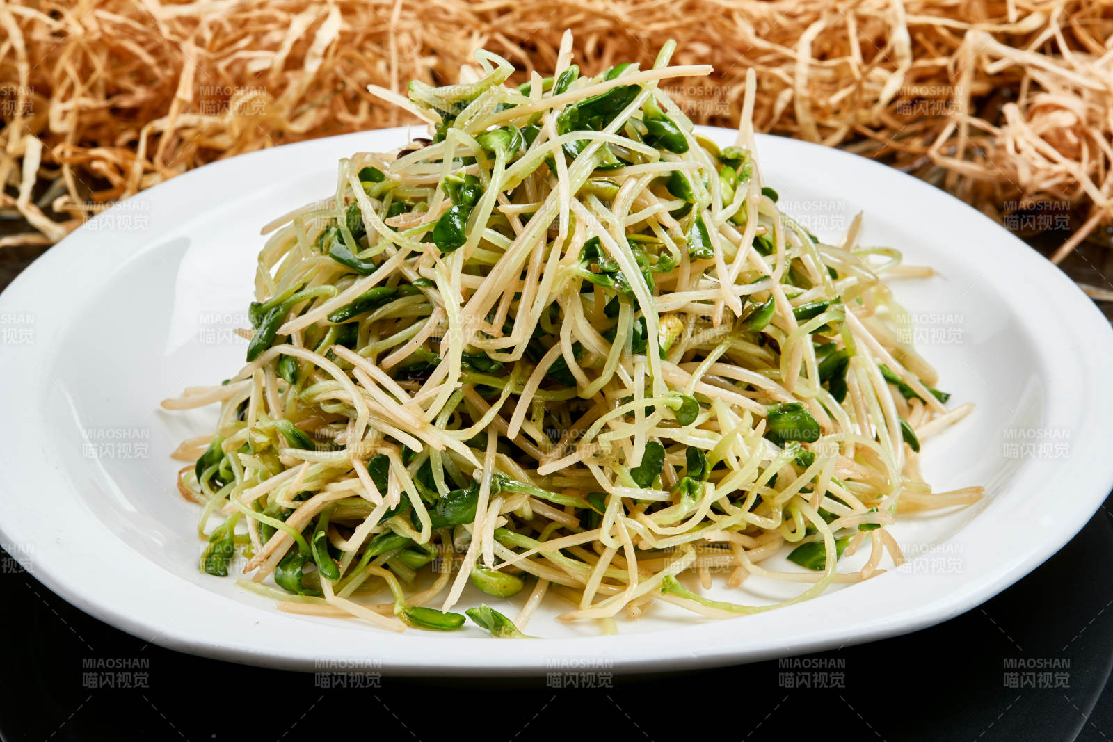 白色瓷盘装的凉拌香椿黑豆苗图片