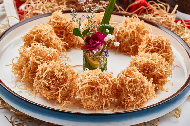 白色瓷盘装的金丝油炸大虾球图片