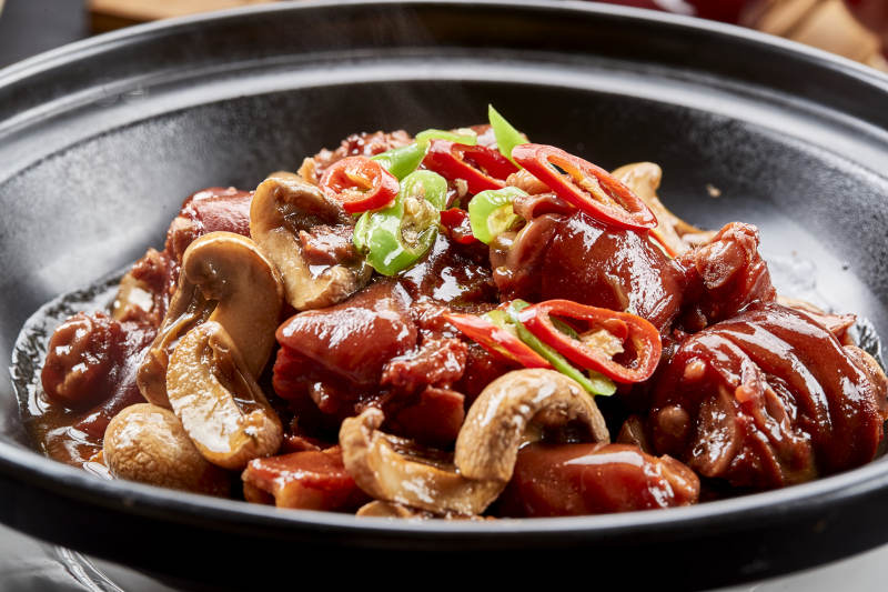 黑砂锅装的砂锅鲜口蘑烧猪脚块图片