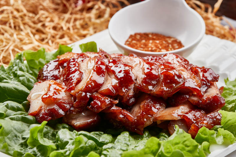 白色瓷盘装的蜜汁叉烧鸡腿肉图片