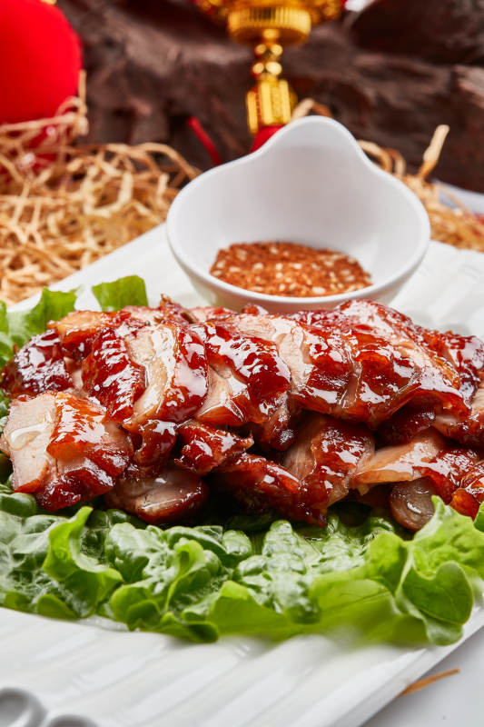 白色瓷盘装的蜜汁叉烧鸡腿肉图片